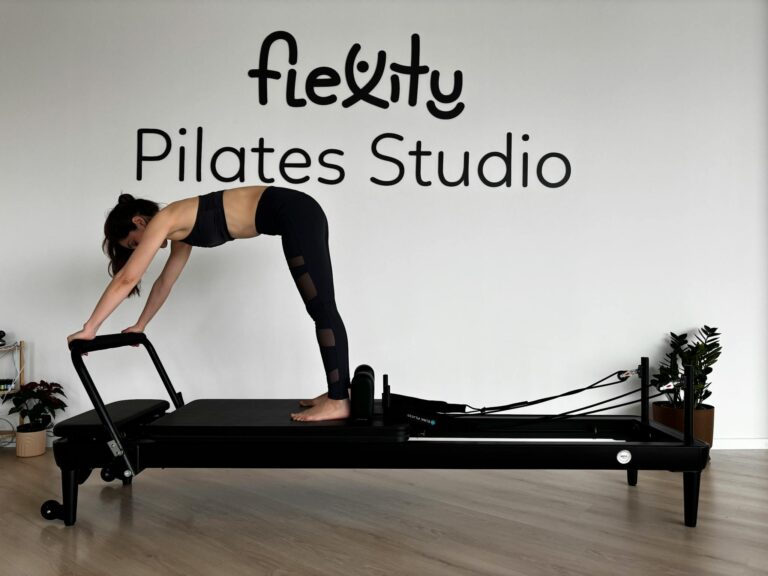 Woman performing Pilates on reformer machine in minimalist studio.